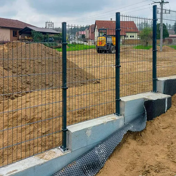 Antracitové 2D panely na sloupcích s patkami na betonové podezdívce, realizace v Přelouči 2026
